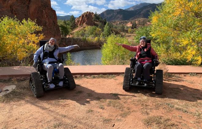 Two TRP participants take a photo in red rock canyon on their accessible trail chairs.