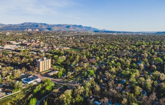 aerial view of neighborhood full of trees. mountains in the background.